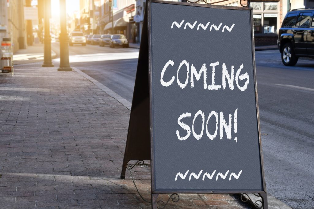 Chalkboard sign on sidewalk proclaiming Coming Soon!